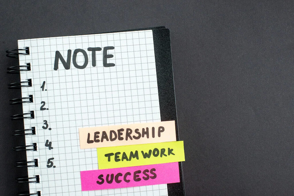 Блокнот із написом note, нумерованим списком і наліпками leadership, teamwork, success