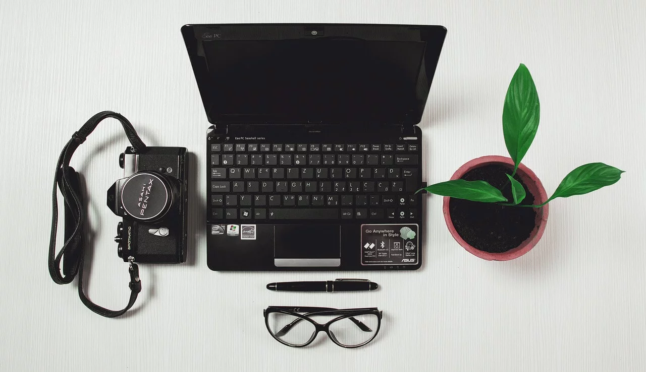 Flat lay of digital tools for webinars including a laptop, camera, and pen
