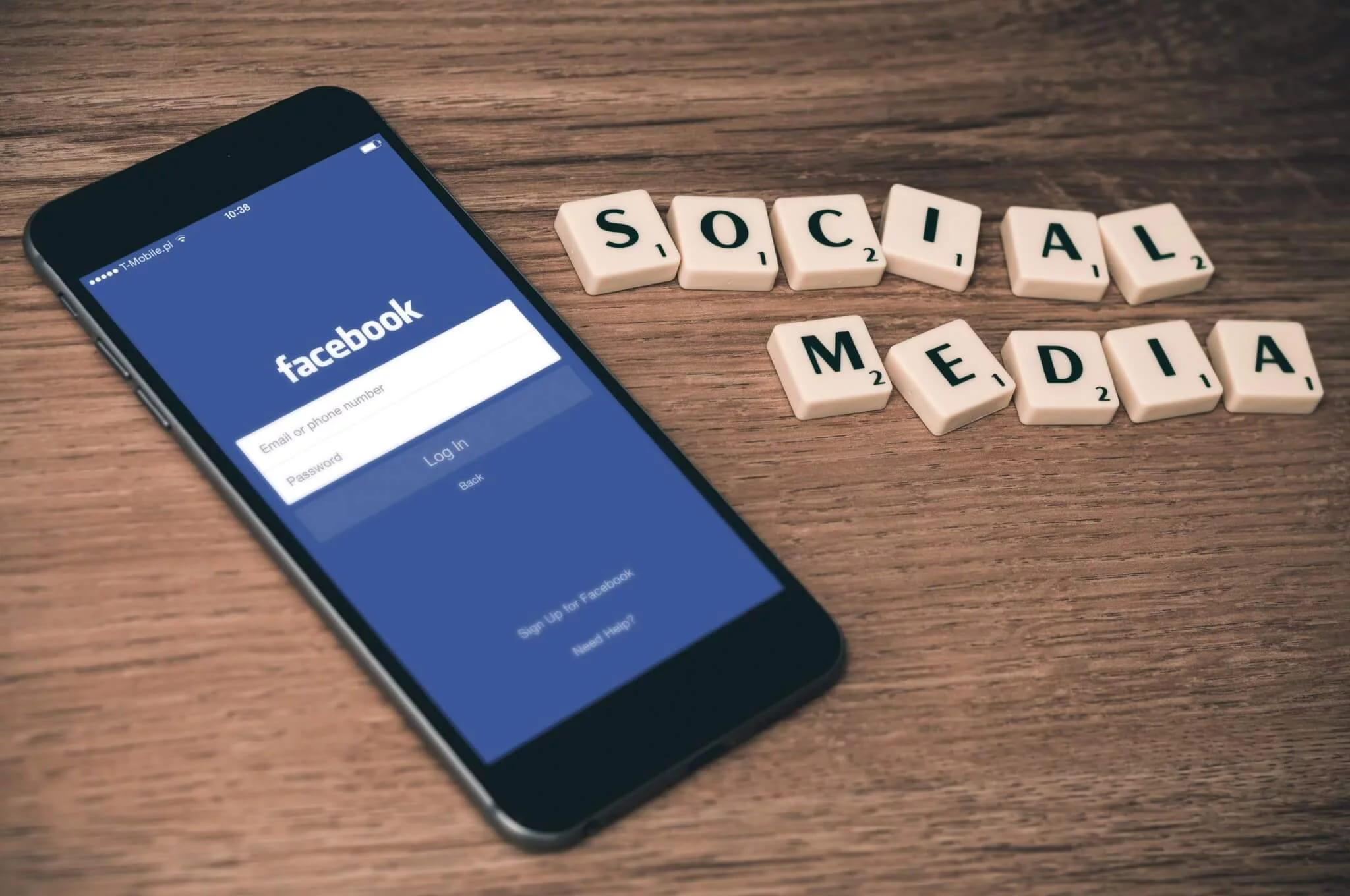 A phone showing the Facebook login screen beside scrabble tiles spelling social media