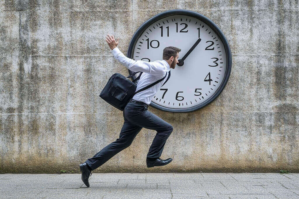 Man running with a briefcase in front of a giant clock, symbolizing urgency and time pressure