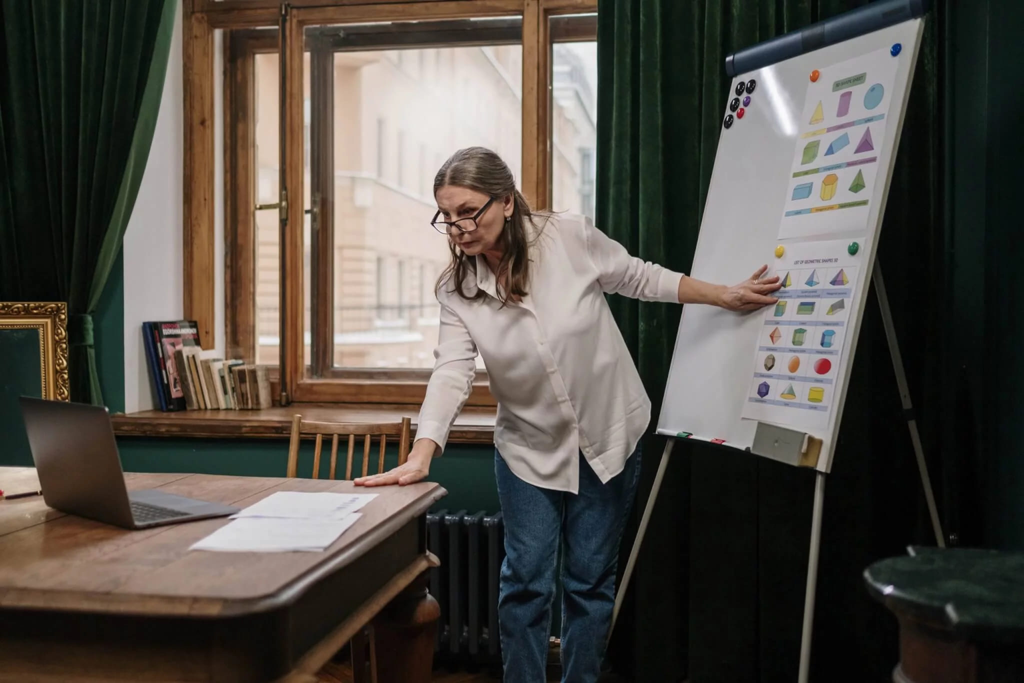 A woman at a flip chart covered with coloured notes, a laptop and papers on the table beside her