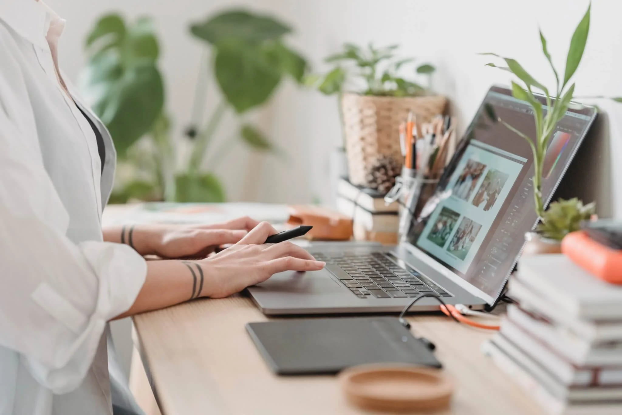 A designer at a desk reviewing work on a laptop with a graphics tablet and stylus