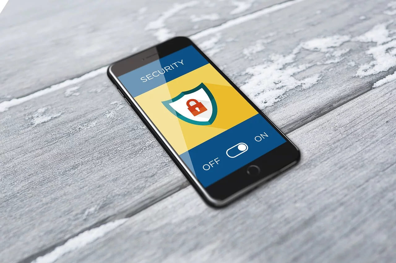 A phone on weathered boards showing a security screen with a padlock shield and the switch turned on